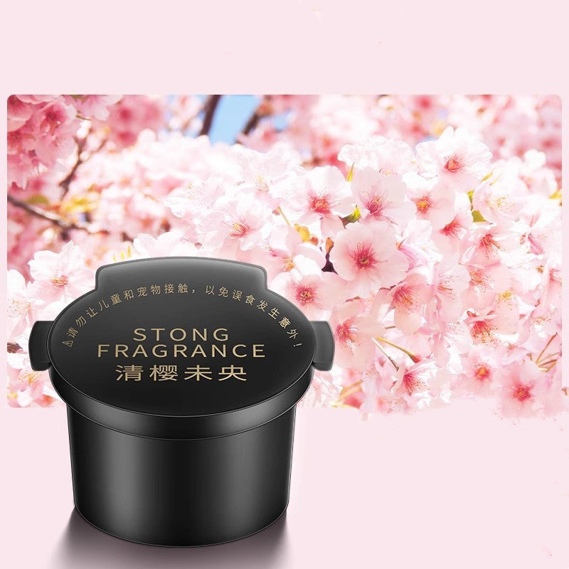 Diffuseur d'aromathérapie Nuvexer noir pour voiture avec parfum naturel, design élégant devant des fleurs de cerisier